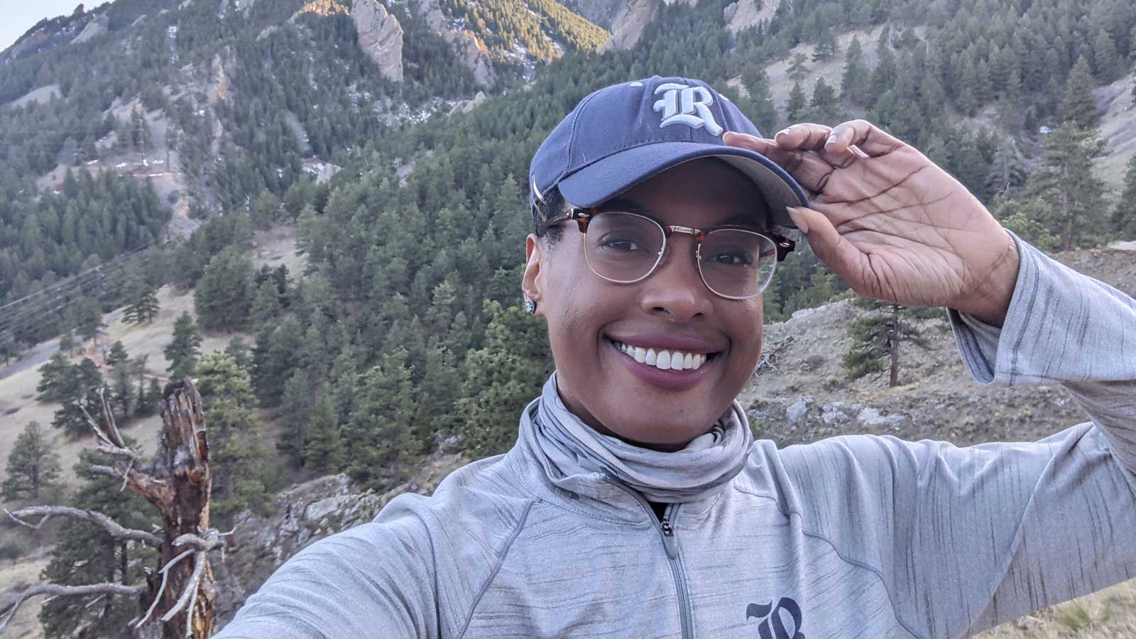 Sydney Gibson wearing Rice University cap standing in front of a mountain